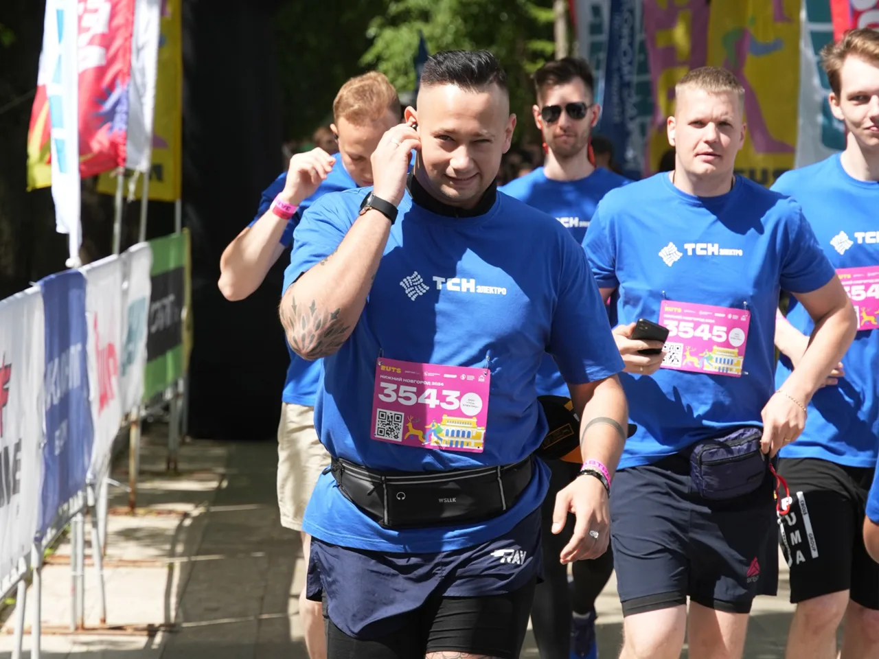 Группа участников забега "Беги, герой!" из команды ТСН-электро в синей спортивной форме, с номерами на груди, бежит по трассе.